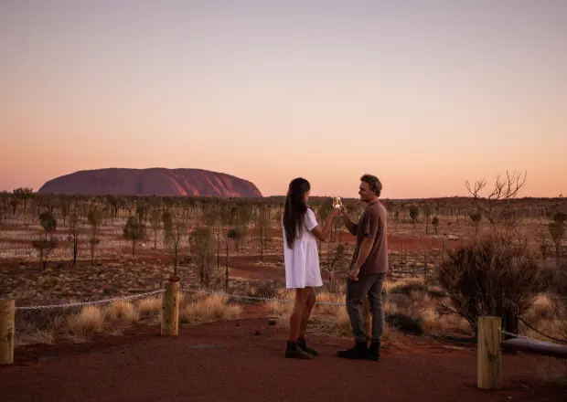Paar genießt ein Glas Wein mit Blick auf den Uluru